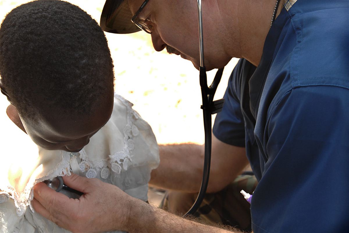 A doctor examining a child with a stethoscope during a community health outreach in Uganda
